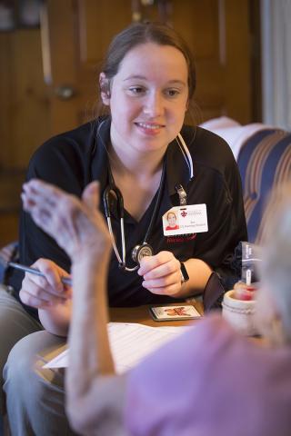 Nursing student listens to an elderly patient seated in her home.